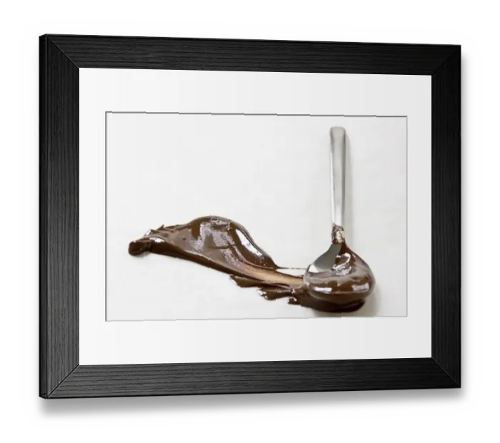 Framed Print : Melted chocolate smeared across white surface with a spoon leaving a plume shape