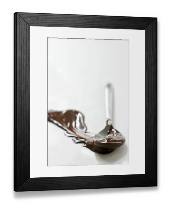 Framed Print : Melted chocolate smeared across white surface with a spoon leaving a plume shape