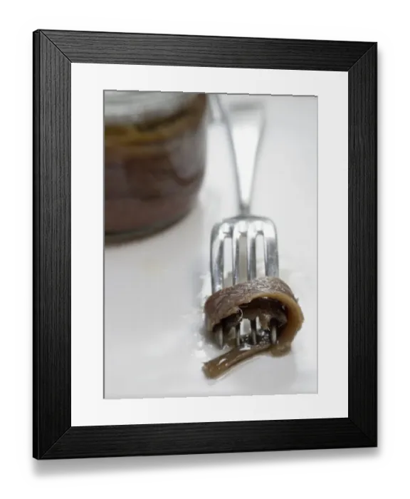 Framed Print : Fillets of anchovies in oil in preserving jar, with single fillet on a fork credit