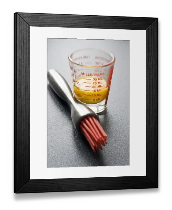 Framed Print : Egg yolk in small glass measuring glass with modern pastry brush with red silicone