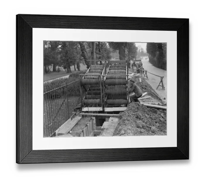 Framed Print : Bundles of telephone cables on a cradle that are being laid underground by workers Framed Print : Bundles of telephone cables on a cradle that are being laid underground by workers