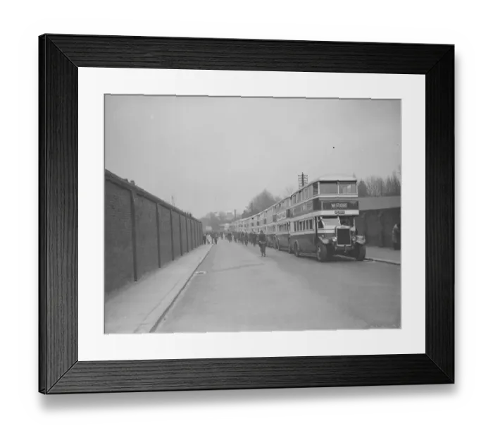 Framed Print : Buses parked on the road outside Chatham dockyard. Dock workers cycling past