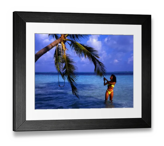 Framed Print : Little Bandos, an island ion the Maldives. With girl tugging at a palm tree