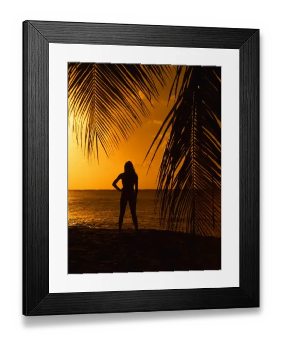 Framed Print : Girl on beach at sunset, seen through palm leaves Framed Print : Girl on beach at sunset, seen through palm leaves