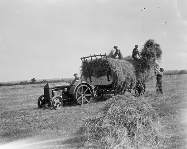 Farm workers in Farningham load hay on to the trailer being pulled by a tractor. 1935