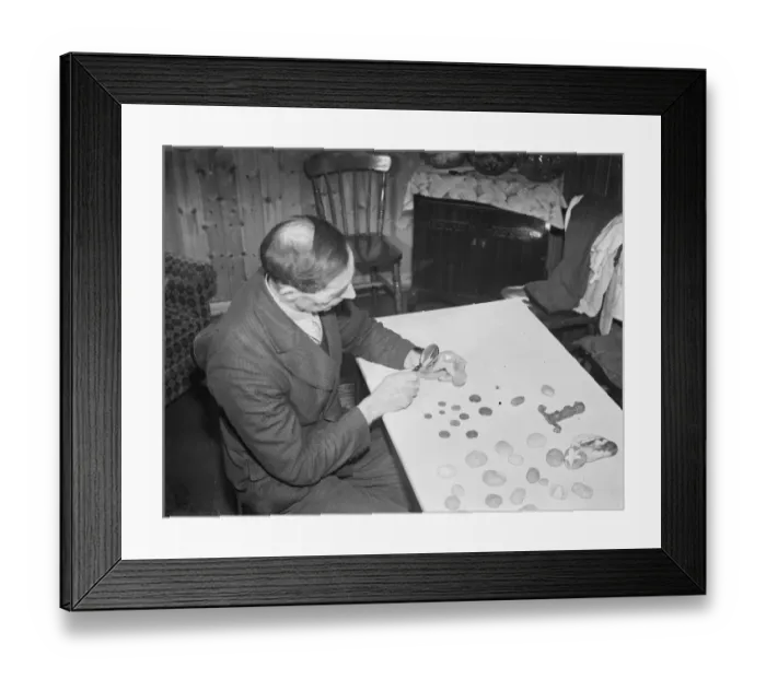 Framed Print : Mr Charles Epps, a beach comber, uses a magnifying glass to inspect his find in