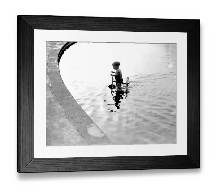 Framed Print : Toddler trying to ride his trike in the water. 1933 Framed Print : Toddler trying to ride his trike in the water. 1933