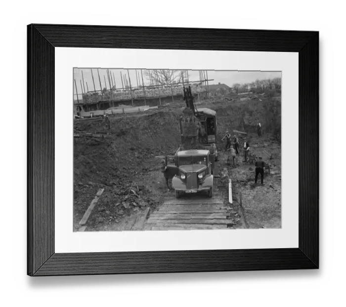 Framed Print : Digger clears the land and puts soil into the back of Bedford truck on the site of Framed Print : Digger clears the land and puts soil into the back of Bedford truck on the site of