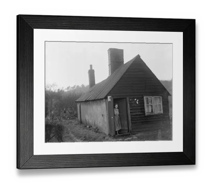 Framed Print : A women stands in the doorway of a cottage that was once a mortuary