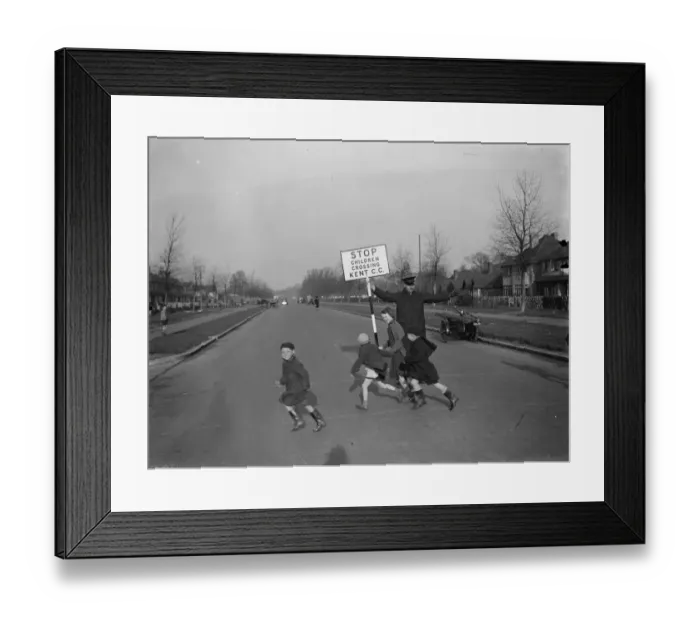 Framed Print : Road attendant from Kent County Council, holding a sign, helps children in St Mary Framed Print : Road attendant from Kent County Council, holding a sign, helps children in St Mary