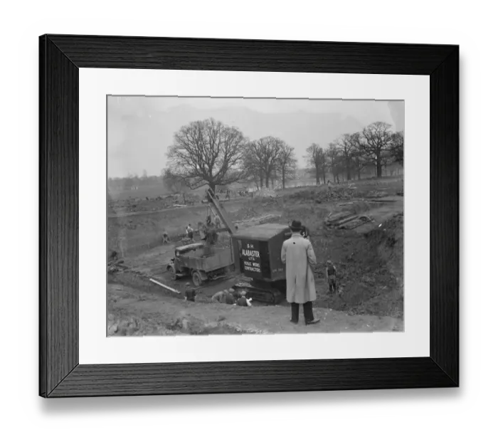 Framed Print : Digger clears the land and puts soil into the back of Bedford truck, on the site