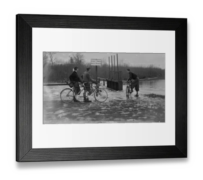 Framed Print : Cyclists look at the high water levels and flooding at the sluice by the river Framed Print : Cyclists look at the high water levels and flooding at the sluice by the river