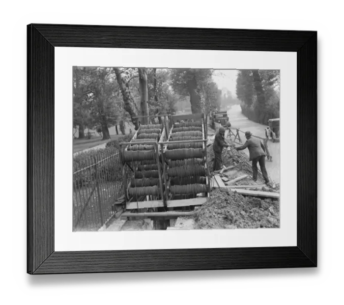 Framed Print : Bundles of telephone cables on a cradle that are being laid underground by workers Framed Print : Bundles of telephone cables on a cradle that are being laid underground by workers