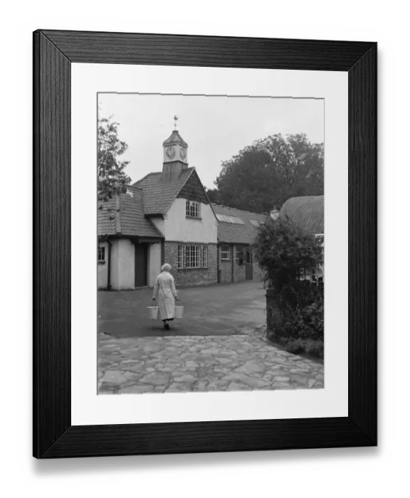 Framed Print : Woman carrying pails on a farm with new barn and clock tower. 1935