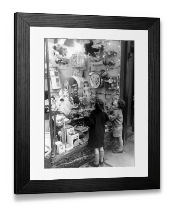 Framed Print : A couple of children look longingly at the wonderful toys on display in their local
