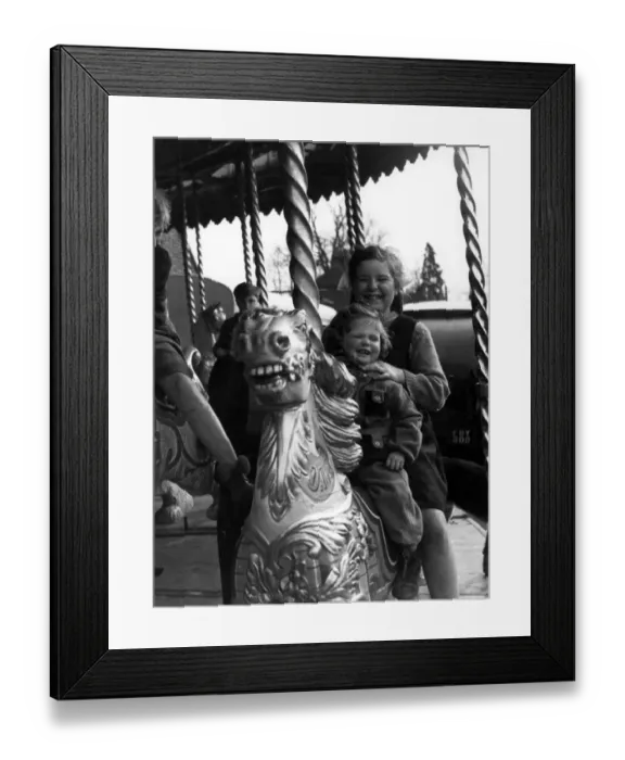 Framed Print : Two girls sitting on a horse on the merry-go-round at the Funfair