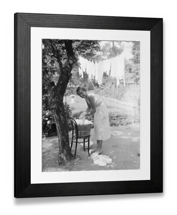 Framed Print : Washing day; A smiling young housewife doing the washing in a tin bath and then