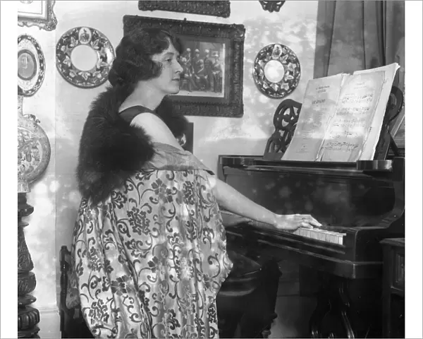 English actress, Miss Marjorie Hume seated at her piano
