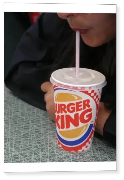 Print : Sucking a soft drink out of a straw in a colourful Burger King disposable cup with a plastic lid Print : Sucking a soft drink out of a straw in a colourful Burger King disposable cup with a plastic lid