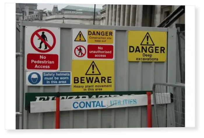 Print : Warning notices on a metal screen outside a construction site in Trafalgar Square