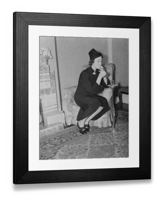 Framed Print : Miss Muriel Oxford sits by the fire having a cigarette Framed Print : Miss Muriel Oxford sits by the fire having a cigarette