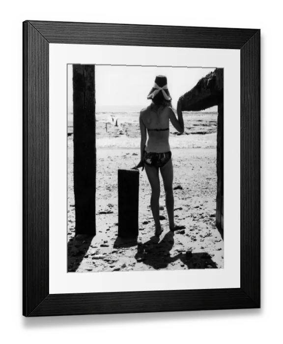 Framed Print : Ann Powys - A woman in the 1960s in a bikini on the beach wearing a straw sun hat