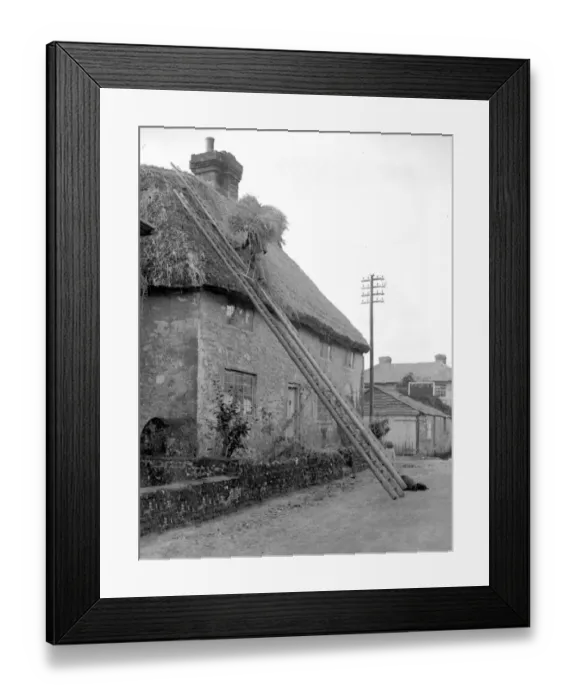 Framed Print : The craft of thatching - The thatcher at work on a picturesque Cottage at Amberley, Sussex