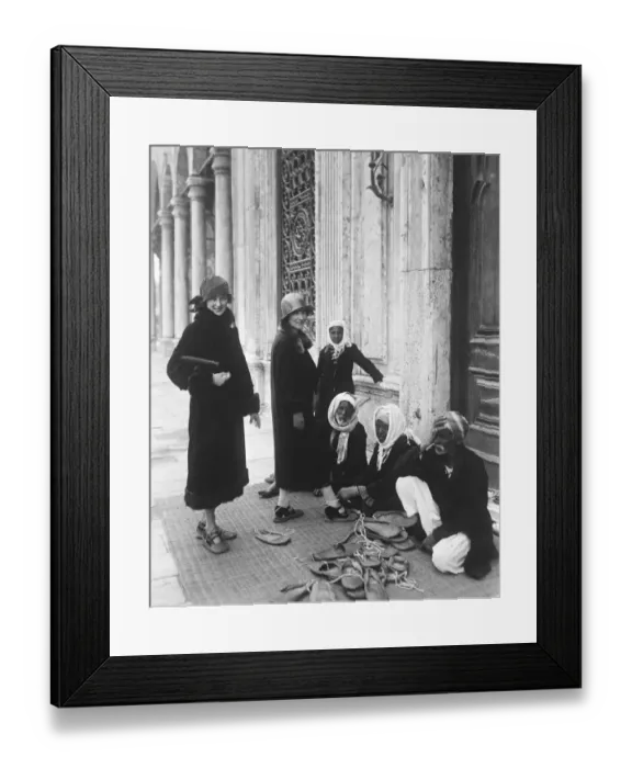 Framed Print : A preliminary to sight seeing. Tourists putting on special shoes before entering