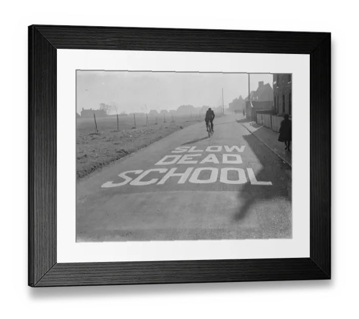 Framed Print : A school sign painted on the road warning road users they are approaching a school area Framed Print : A school sign painted on the road warning road users they are approaching a school area