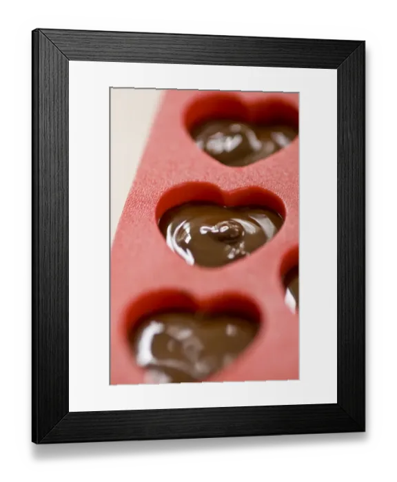 Framed Print : Making heart shaped in chocolates for Valentines day in red heart shaped mould credit Framed Print : Making heart shaped in chocolates for Valentines day in red heart shaped mould credit