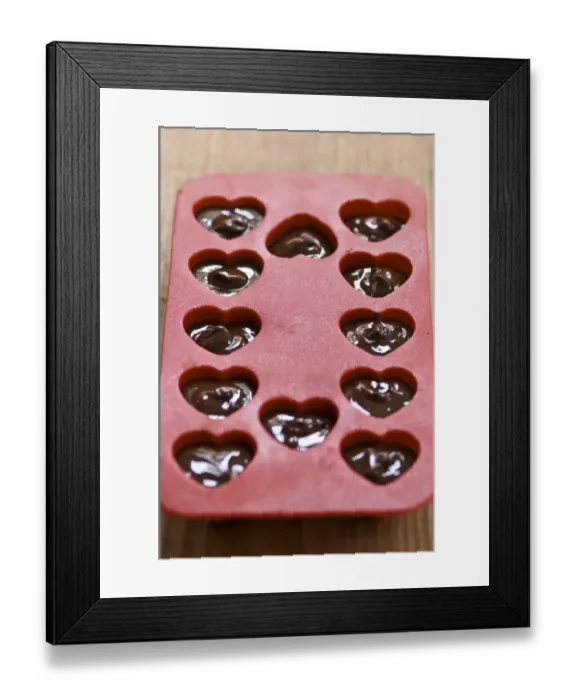 Framed Print : Making heart shaped in chocolates for Valentines day in red heart shaped mould credit Framed Print : Making heart shaped in chocolates for Valentines day in red heart shaped mould credit