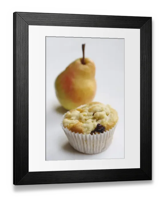 Framed Print : Raisin muffin in plain paper case, topped with grated pear and with whole pear behind Framed Print : Raisin muffin in plain paper case, topped with grated pear and with whole pear behind