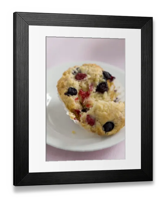 Framed Print : Fresh berry muffin with raspberries and blueberries, torn open on white plate Framed Print : Fresh berry muffin with raspberries and blueberries, torn open on white plate