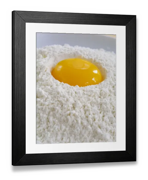 Framed Print : A whole egg yolk broken into a pile of sifted flour credit: Marie-Louise Avery