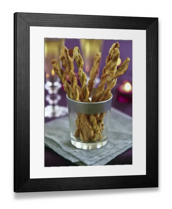 Framed Print : Twisted cheese straws in silver rimmed glass in candlelit party setting credit