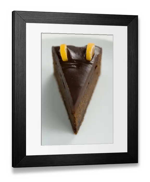Framed Print : Slice of rich dense dark chocolate cake with shiny choc topping and candied orange Framed Print : Slice of rich dense dark chocolate cake with shiny choc topping and candied orange