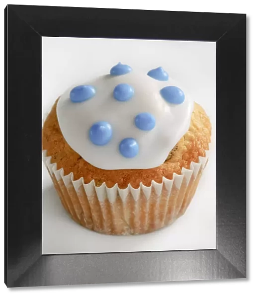 Iced cupcake with blue spots on white icing credit: Marie-Louise Avery  /  thePictureKitchen