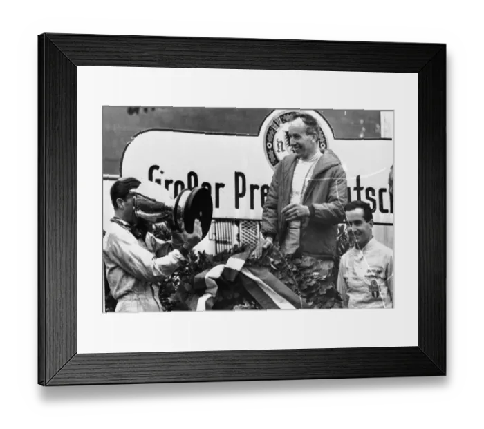 Framed Print : John Surtees looks smilingly on as Graham Hill drinks Champagne out of the Gian Cup