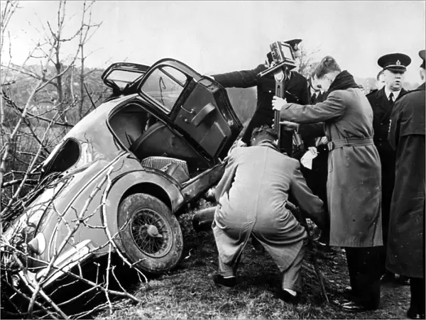 Police and photorgraphers are seen with the wreck of the black Jaguar car in which