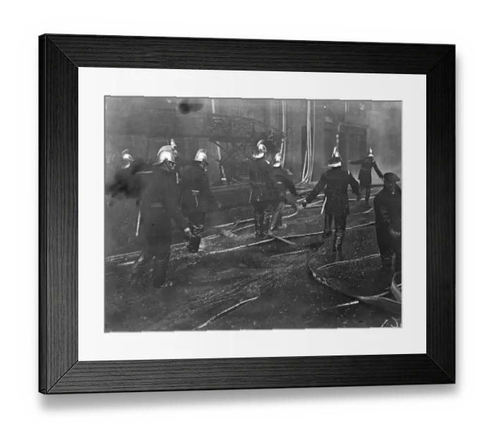 Framed Print : Firemen wallow in molten rubber as warehouse blazes still. Firemen wading through