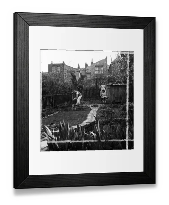 Framed Print : Man Gardening, while children play on swing 1946 [no caption, location or date]