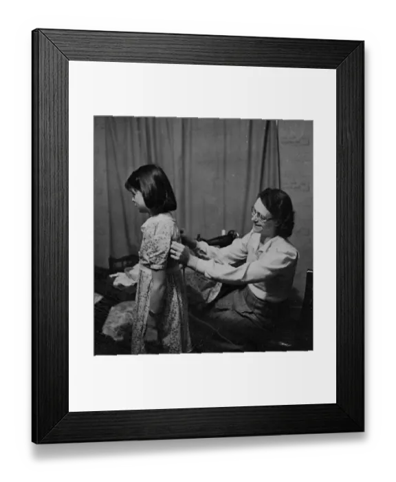 Framed Print : Woman sewing using a sewing machine and fitting a young girls dress [no caption Framed Print : Woman sewing using a sewing machine and fitting a young girls dress [no caption