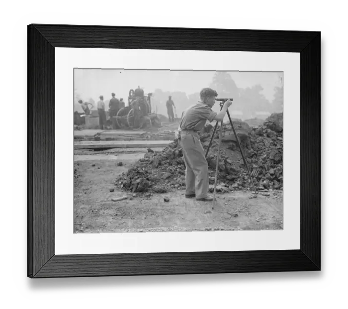 Framed Print : A surveyor at work during the excavations on the site of a bomb proof shelter to Framed Print : A surveyor at work during the excavations on the site of a bomb proof shelter to