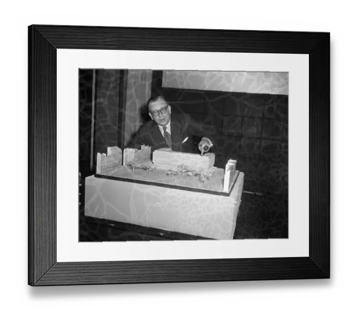 Framed Print : Eero Saarinen, the famous Finnish architect points out features in his model of his Framed Print : Eero Saarinen, the famous Finnish architect points out features in his model of his