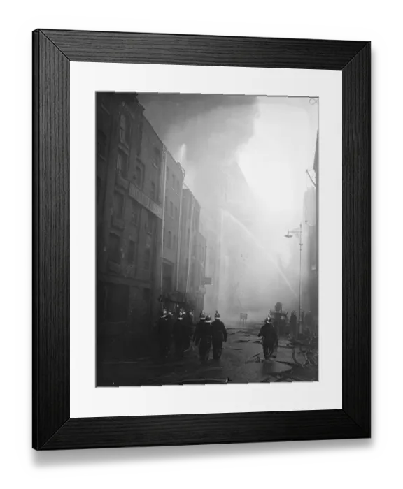 Framed Print : Firemen wallow in molten rubber as warehouse blazes still. Firemen wading through