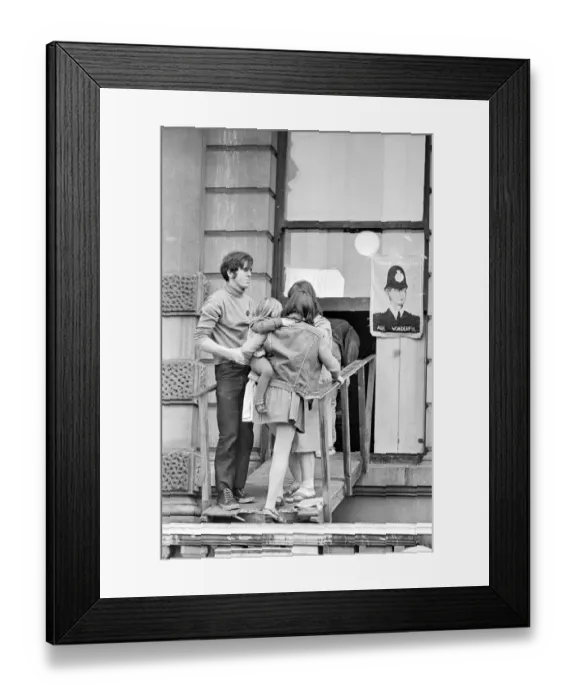 Framed Print : London: A women and child is assisted by squatters to enter the empty 60 room mansion a 144