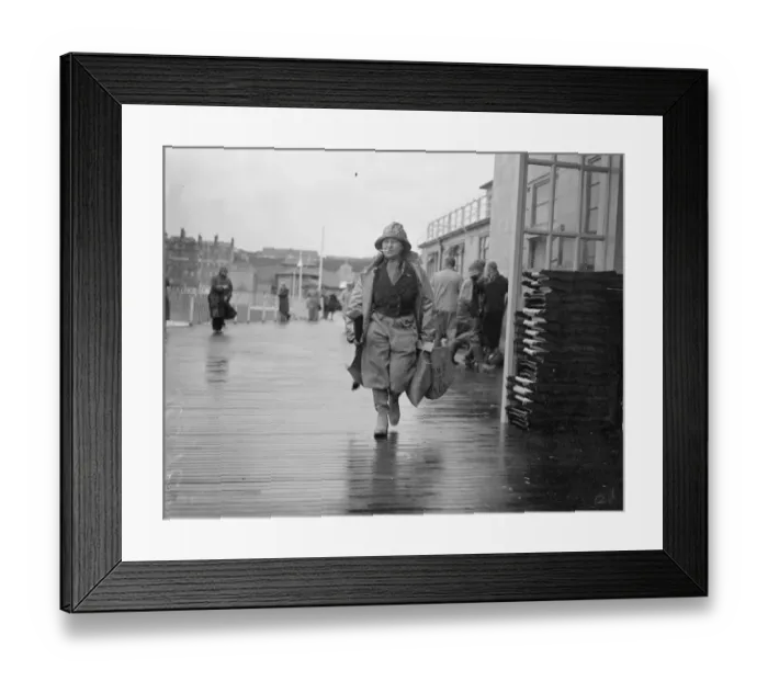 Framed Print : Women angler defies the gales at Hastings. With a stiff gale whipping up the sea