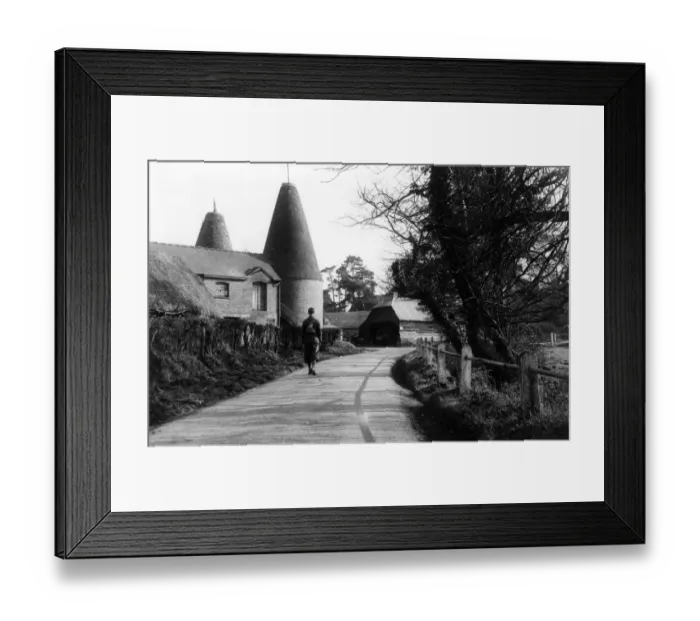 Framed Print : A man walks down a country road passing an oast house, near Penshurst, Kent, England