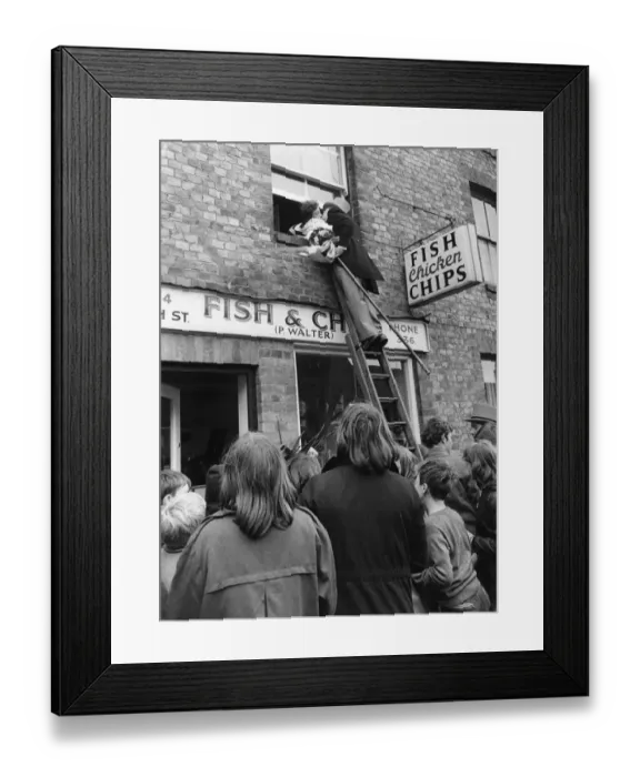 Framed Print : The bridegroom climbs a ladder to kiss his bride at the window above a fish and chip shop Framed Print : The bridegroom climbs a ladder to kiss his bride at the window above a fish and chip shop
