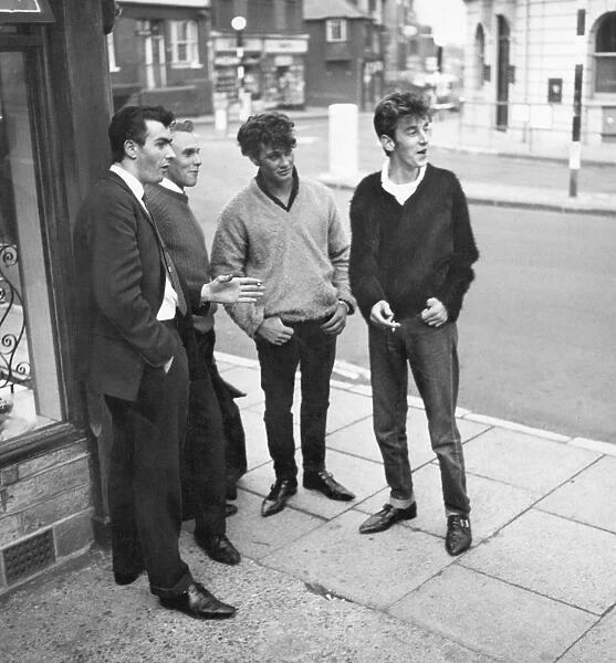 1962 Men standing on a street corner in East Grinstead, West Sussex watching girls go by